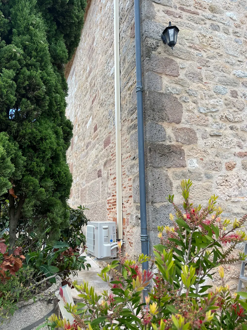 Installation d'une climatisation vu de l'extérieur avec de la verdure